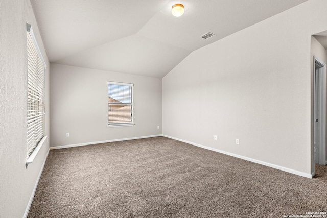 unfurnished bedroom with visible vents, carpet, baseboards, and vaulted ceiling