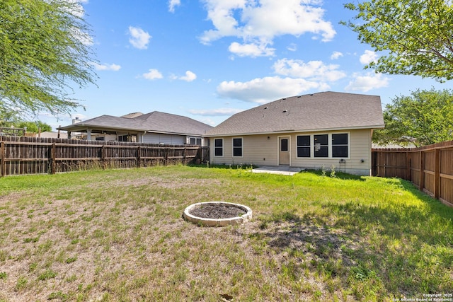rear view of house with a fenced backyard, a patio, and a lawn
