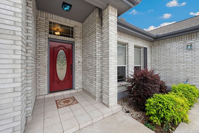 doorway to property with brick siding and roof with shingles