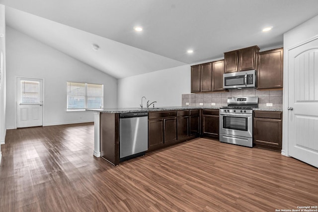 kitchen with dark brown cabinetry, dark wood-style flooring, appliances with stainless steel finishes, tasteful backsplash, and vaulted ceiling