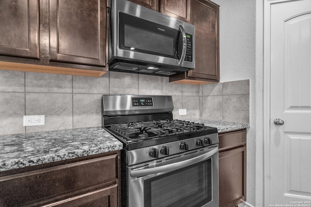 kitchen featuring appliances with stainless steel finishes, decorative backsplash, light stone countertops, and dark brown cabinets