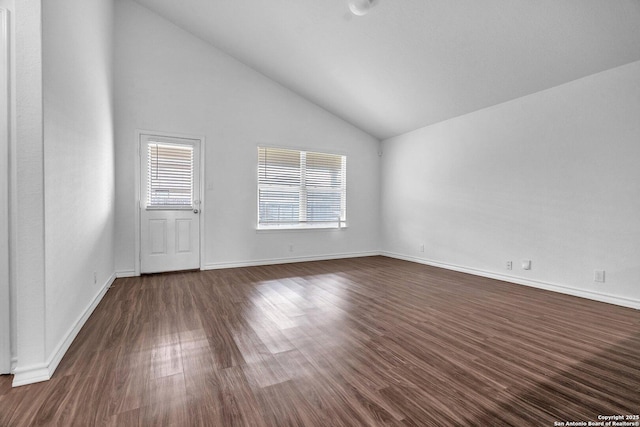 spare room with a healthy amount of sunlight, baseboards, vaulted ceiling, and dark wood-type flooring