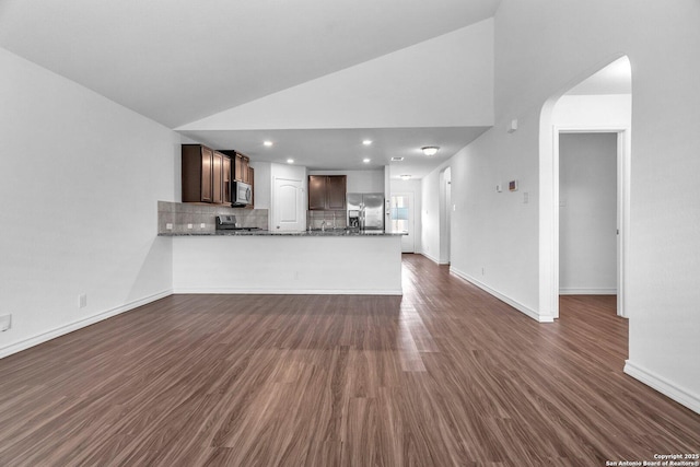 unfurnished living room featuring dark wood-style flooring, high vaulted ceiling, baseboards, and arched walkways