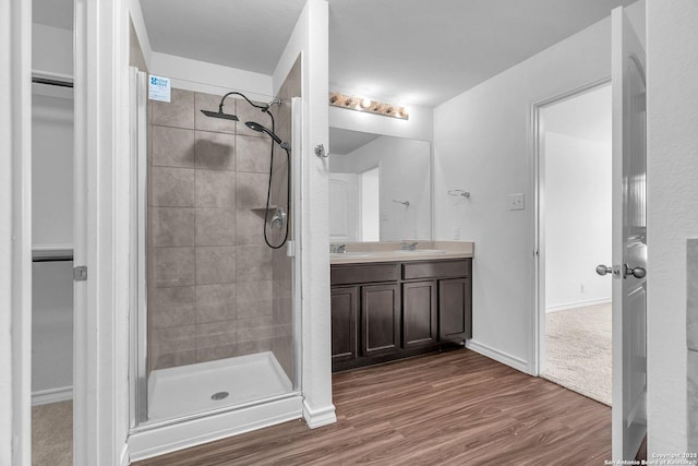 full bathroom with wood finished floors, a sink, and a stall shower