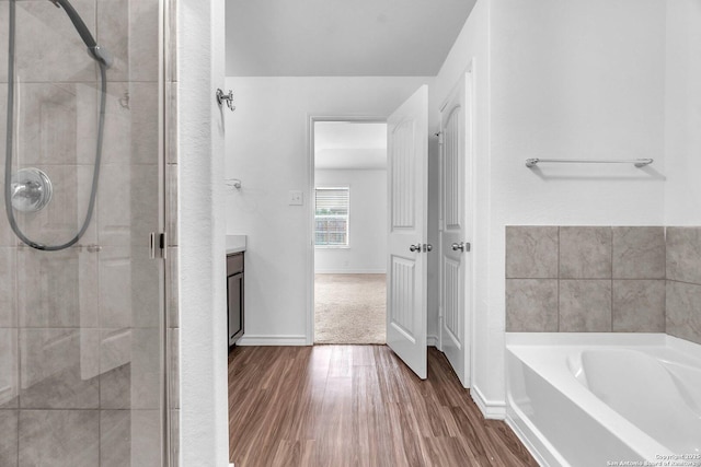 full bathroom with vanity, baseboards, wood finished floors, a garden tub, and a stall shower