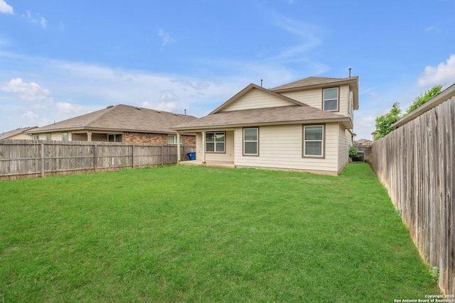 rear view of property with a fenced backyard, a yard, and roof with shingles