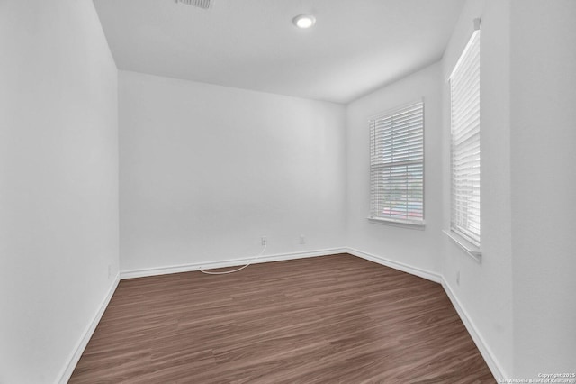 spare room featuring baseboards, visible vents, and dark wood-style floors