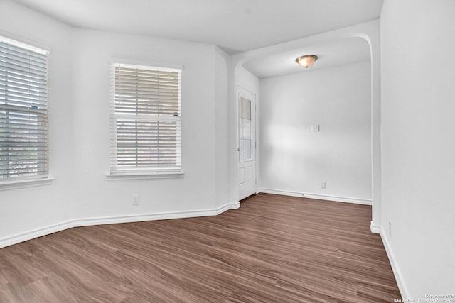 spare room featuring baseboards and dark wood-type flooring