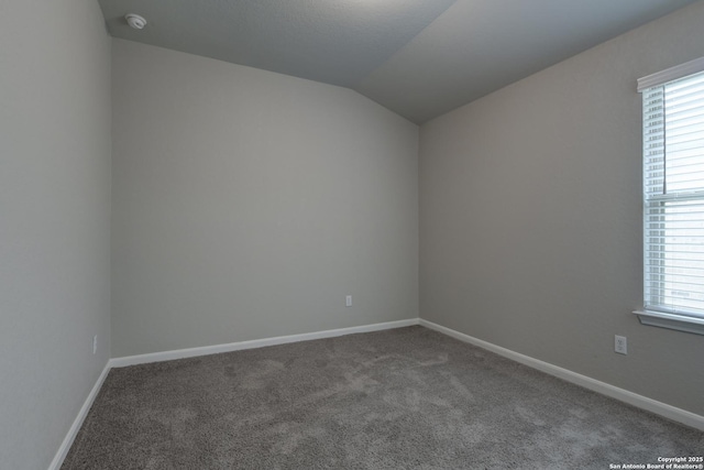 carpeted empty room with baseboards, vaulted ceiling, and a wealth of natural light