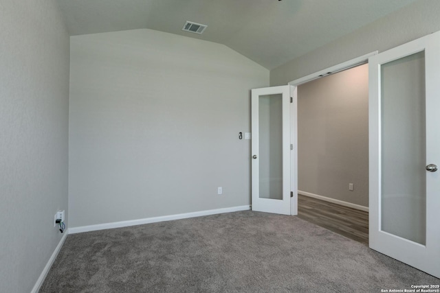 carpeted empty room featuring french doors, baseboards, vaulted ceiling, and visible vents