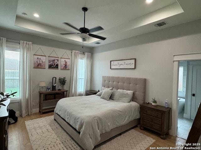 bedroom featuring visible vents, recessed lighting, a raised ceiling, and light wood-style floors