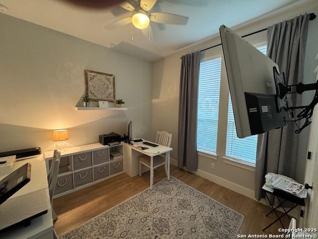 home office with plenty of natural light, a ceiling fan, and wood finished floors
