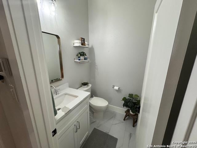 bathroom with toilet, baseboards, marble finish floor, and vanity