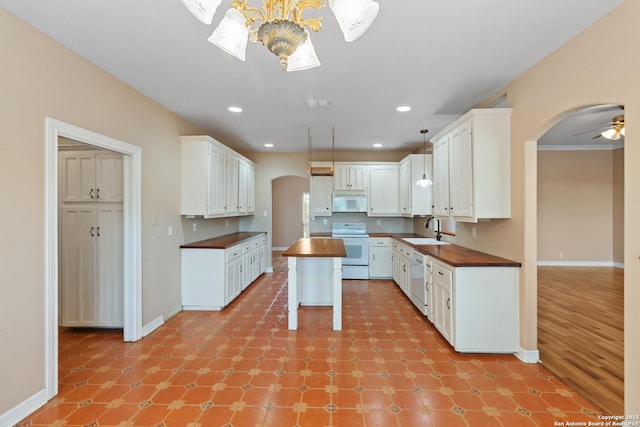 29303 Sumpter Dr, Boerne, TX 78015 - kitchen featuring a sink, white appliances, arched walkways, wooden counters, and baseboards