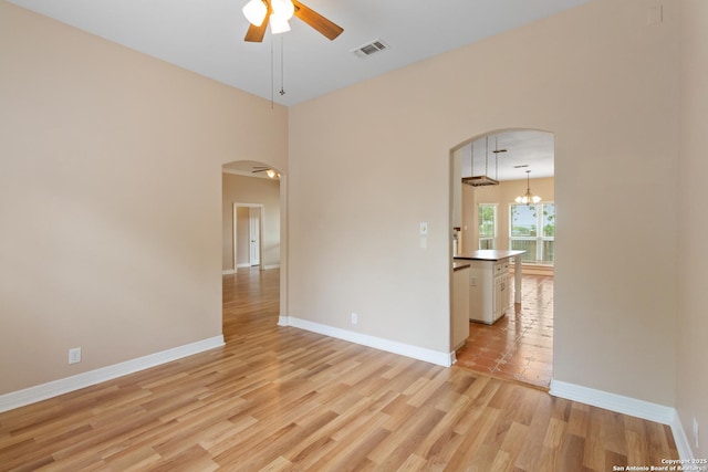 29303 Sumpter Dr, Boerne, TX 78015 - empty room with visible vents, baseboards, ceiling fan, arched walkways, and light wood-style flooring