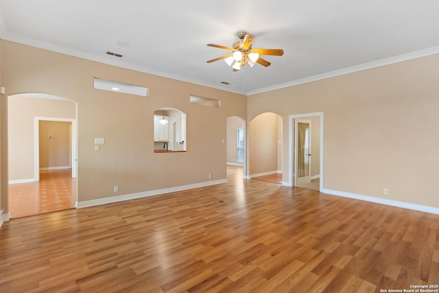 29303 Sumpter Dr, Boerne, TX 78015 - unfurnished living room with light wood-style floors, arched walkways, a ceiling fan, baseboards, and ornamental molding