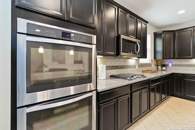 kitchen with decorative backsplash, recessed lighting, light stone counters, appliances with stainless steel finishes, and light tile patterned floors