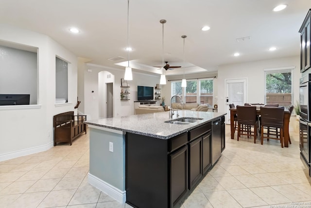 kitchen featuring light tile patterned flooring, dishwashing machine, an island with sink, arched walkways, and a sink