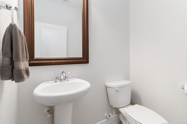 bathroom featuring baseboards, a sink, and toilet