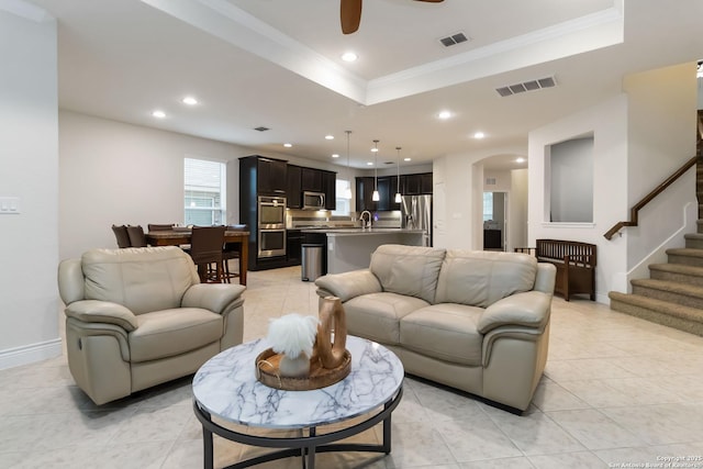 living area with crown molding, arched walkways, a tray ceiling, and visible vents
