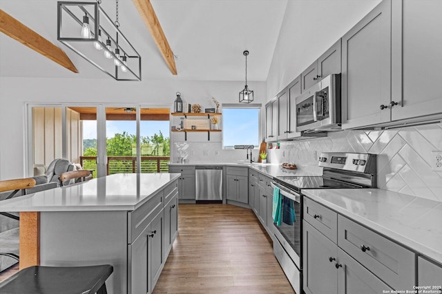 kitchen featuring appliances with stainless steel finishes, tasteful backsplash, a breakfast bar area, light wood-type flooring, and gray cabinetry