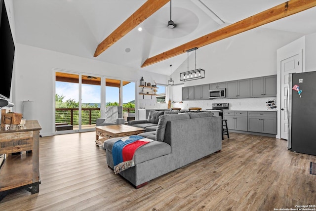 living area with high vaulted ceiling, ceiling fan, light wood-style flooring, and beam ceiling