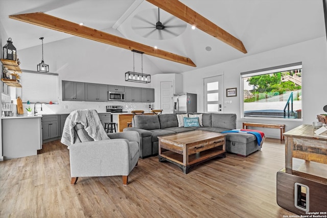 living area with a ceiling fan, beamed ceiling, light wood-style flooring, and high vaulted ceiling