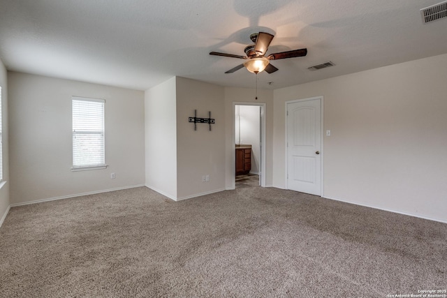carpeted empty room featuring baseboards, a ceiling fan, and visible vents