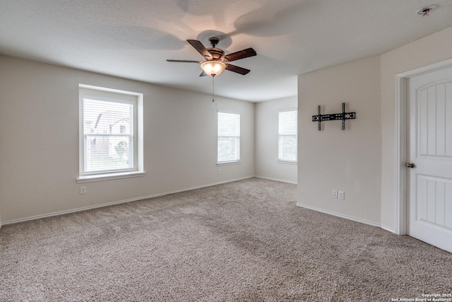 carpeted empty room featuring ceiling fan and baseboards