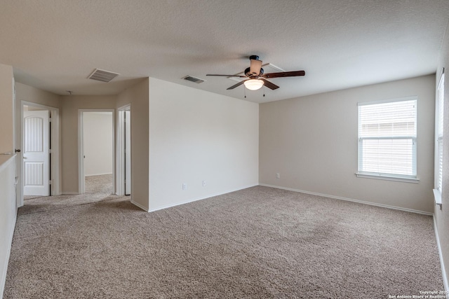carpeted spare room featuring a textured ceiling, ceiling fan, visible vents, and baseboards