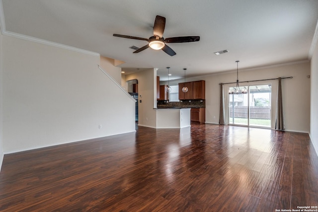 unfurnished living room with crown molding, ceiling fan with notable chandelier, dark wood-type flooring, and visible vents