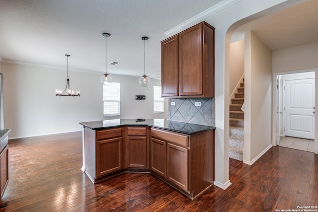 kitchen with crown molding, arched walkways, a peninsula, backsplash, and dark wood-style floors