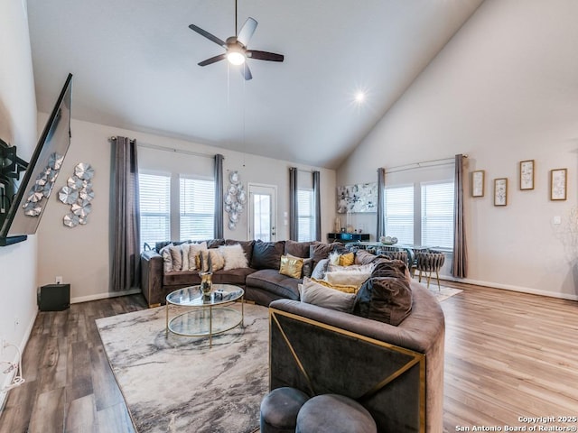 living room with a ceiling fan, wood finished floors, a wealth of natural light, and high vaulted ceiling