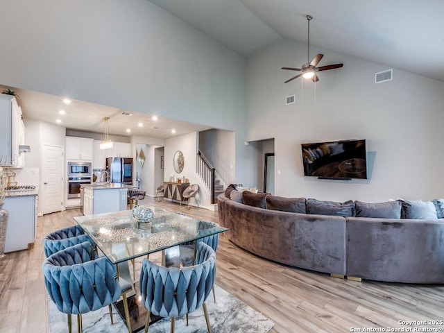 dining room featuring stairway, ceiling fan, light wood-type flooring, and visible vents