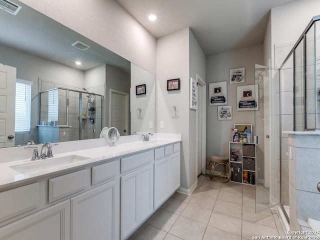 bathroom featuring a sink, tile patterned flooring, a shower stall, and visible vents
