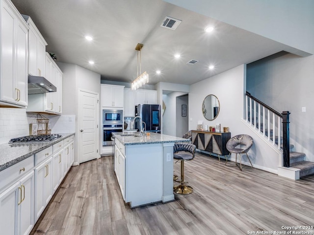 kitchen with visible vents, stainless steel appliances, tasteful backsplash, under cabinet range hood, and light wood-style flooring