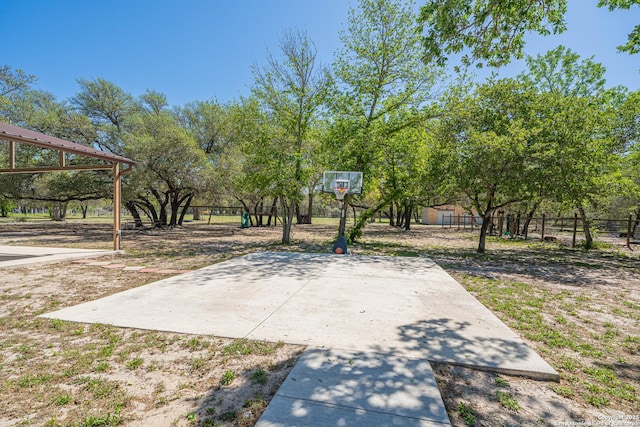 view of basketball court featuring fence and basketball hoop
