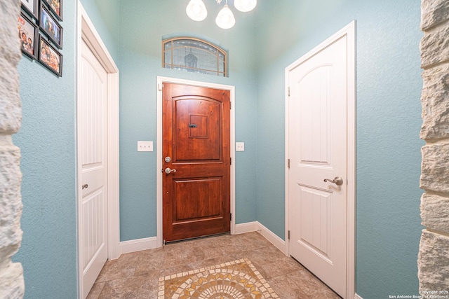entrance foyer with baseboards, a notable chandelier, and tile patterned flooring