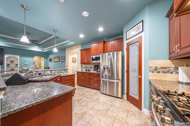 kitchen featuring arched walkways, appliances with stainless steel finishes, decorative backsplash, and a sink