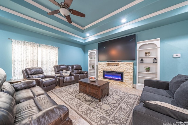 living room featuring built in features, ornamental molding, a fireplace, and ceiling fan