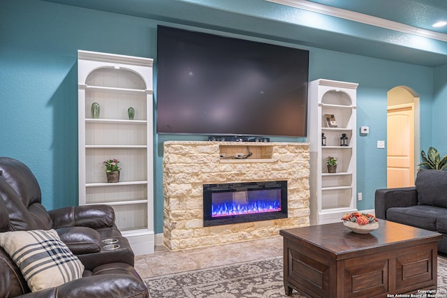 living area with arched walkways, a stone fireplace, and built in features