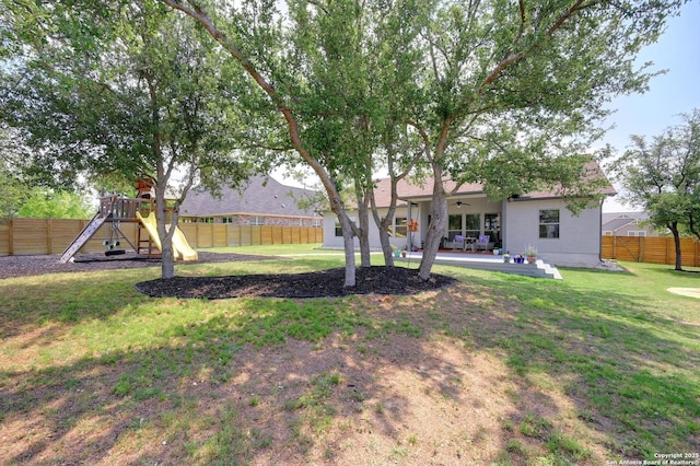 view of yard with a fenced backyard, ceiling fan, a playground, and a patio area