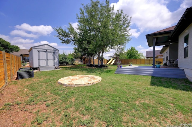 view of yard with a storage unit, a fenced backyard, a playground, and an outdoor structure