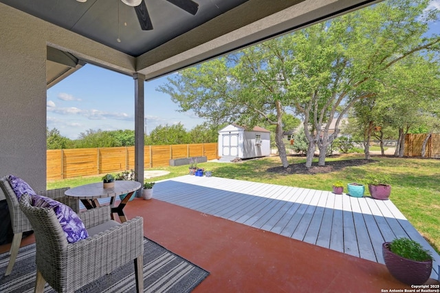 view of patio / terrace with a storage shed, ceiling fan, a deck, a fenced backyard, and outdoor dining area