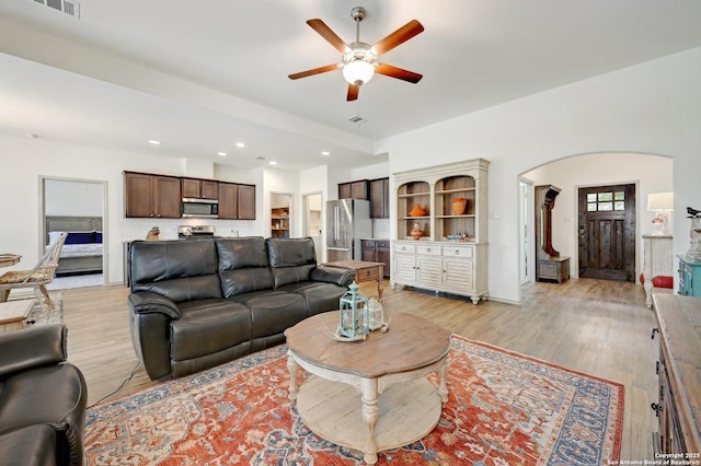 living area featuring ceiling fan, visible vents, arched walkways, light wood-style floors, and recessed lighting