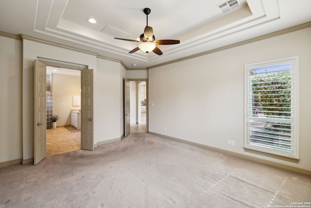 unfurnished bedroom with visible vents, ensuite bathroom, baseboards, light colored carpet, and a raised ceiling