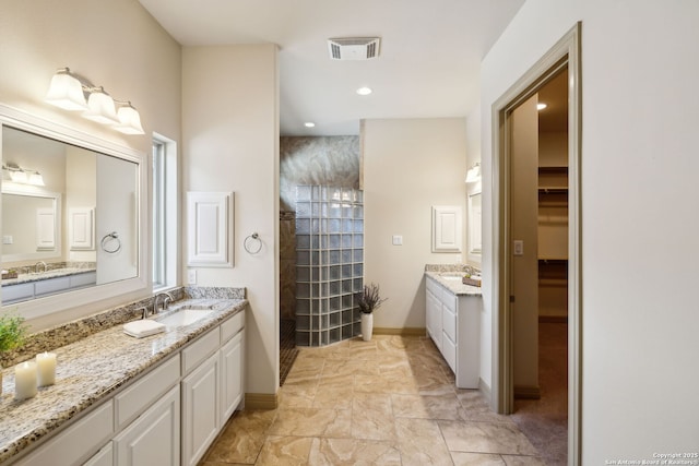 bathroom with baseboards, walk in shower, two vanities, and a sink