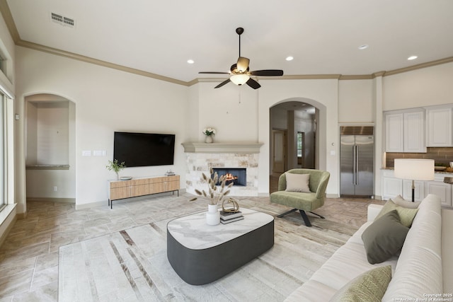 living area featuring visible vents, arched walkways, crown molding, and ceiling fan