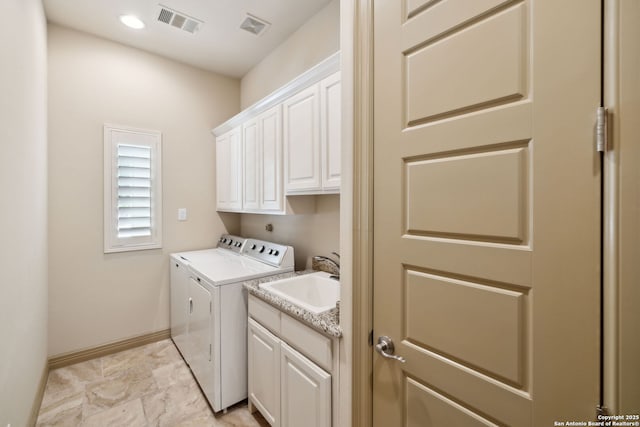 washroom with visible vents, cabinet space, a sink, baseboards, and washer and clothes dryer