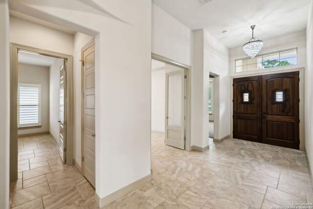 entrance foyer featuring an inviting chandelier, baseboards, and a towering ceiling